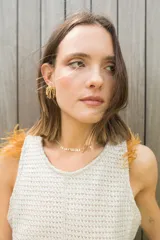 Chaleco color crema de tejido de punto calado, con cuello redondo y detalle de plumas en los hombros.