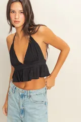 Top blanco con textura y peplum, escote halter y tirantes finos.