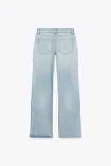 Pantalón de jean celeste claro, de tiro bajo, corte wide leg y largo hasta el tobillo. Tiene cinco bolsillos, cierre frontal con cremallera y botón metálico.