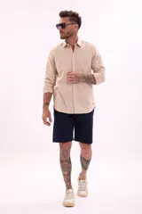 Camisa de manga larga color beige claro, de corte clásico y confeccionada en tejido texturizado.