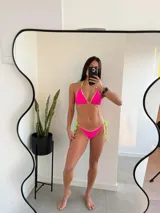 Conjunto de bikini fucsia con ribetes y tiras de ajuste en color verde neón.