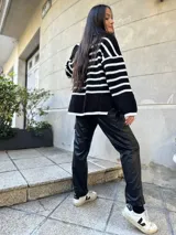 Sweater de punto grueso a rayas horizontales blancas y negras, con cuello alto y mangas largas.