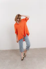 Camisa de lino color coral, de corte amplio, con cuello camisero, botones frontales y mangas 3/4 arremangables.