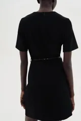 Vestido corto negro con cuello redondo, manga corta y cinturón fino extraíble con hebilla de metal.
