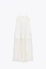 Vestido largo blanco de escote recto y tirantes finos. Falda con tejido plisado combinado a tono.