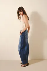 Pantalón jean de tiro alto, corte amplio y pierna ancha con parches en diferentes tonos de azul.