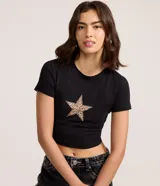 Remera negra de algodón con cuello redondo, manga corta y corte cropped ajustado al cuerpo. Presenta un aplique de estrella con estampado de leopardo en el pecho.