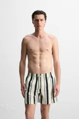 Short de baño blanco con rayas verticales negras y celestes, cintura elástica con cordón ajustable, bolsillos laterales y trasero.