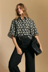 Camisa de manga corta con cuello camisero, confeccionada en tela estampada con diseño paisley en tonos negro, beige y azul.