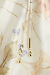 Vestido midi de corte amplio con estampado floral, cuello redondo con frunces, mangas globo 3/4 con puños elásticos, botones frontales y falda con volantes.