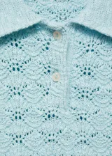 Jersey de crochet color celeste, de manga corta y cuello polo con cierre de botones.