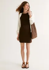 Vestido marrón ajustado al cuerpo, sin mangas y largo hasta la rodilla.