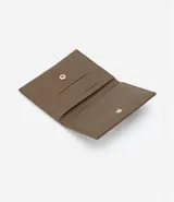 Billetera plegable pequeña color marrón con pespuntes y cierre por enganche. Marca Satinato, colección Otoño/Invierno 2023. Confeccionada en material sintético.