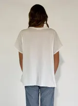 Camisa blanca de lino y algodón con cuello en V, mangas cortas y volados frontales. Cierre con botones.