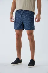 Short de baño azul con estampado de hojas y flores en blanco. Tiene cintura elástica con cordón ajustable, dos bolsillos laterales y uno trasero.