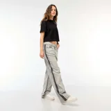 Pantalón de jean gris con lavado ácido y corte holgado. Presenta una franja vertical negra a lo largo de la pierna.