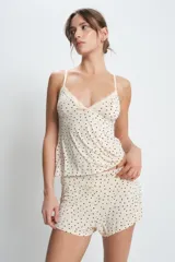 Conjunto de pijama color crema con estampado de lunares negros, compuesto por un top de tirantes con encaje en el escote y un short con cintura elástica.