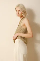 Musculosa de tejido calado color dorado, con cuello redondo y sisas amplias.