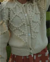 Cárdigan celeste de lana merino con diseño calado en color crudo y botones de nácar.