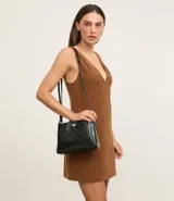 Bolso bandolera pequeño color negro, con textura acolchada en forma de rombos y logo triangular dorado en el frente.