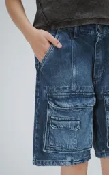 Bermuda de denim azul con efecto lavado, calce oversize y múltiples bolsillos tipo cargo.