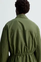 Parka verde militar de corte relaxed fit confeccionada en tejido técnico ligero. Cuello solapa y manga larga. Bolsillos de plastrón con solapa en delantero. Cintura ajustable en interior. Cierre frontal con cremallera oculta por solapa con botones a presión.