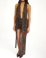 Vestido corto de tela transparente con estampado abstracto en tonos negro, azul oscuro y naranja. Diseño halter con tiras largas que caen al frente y parte inferior fruncida.