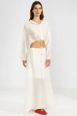 Blusa corta color crema en tejido arrugado liviano, con cuello mao, botones al frente y mangas abullonadas. Terminada con ruedo elastizado.