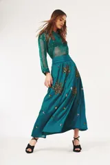 Falda larga color verde azulado con cintura alta y bordados dorados y plateados con forma de hojas.