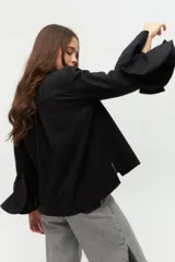 Camisa negra con cuello clásico y mangas largas con detalle de volados en los puños.