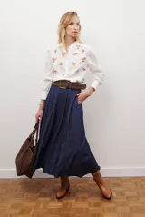 Falda larga de jean azul oscuro, corte acampanado con paneles y costuras visibles.