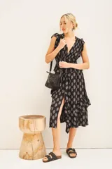 Vestido corto negro con estampado floral blanco, escote en V, volados en mangas y falda, cintura elastizada, frunces en hombros, tajo central y cierre lateral invisible.