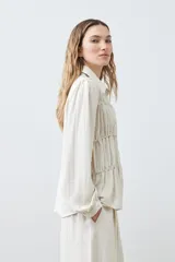 Camisa beige melange con frunces en el frente, de manga larga y cuello camisero.