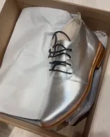 Zapato acordonado plateado de cuero vacuno con suela de madera.