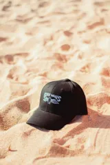 Gorra negra con logo bordado en blanco con la inscripción "Glassy Waves" y dos alas.