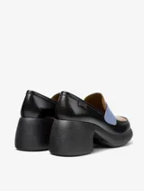Mocasín de cuero vacuno con diseño bicolor en negro y marrón, destacando una banda frontal en color celeste. Presenta un tacón grueso y plataforma de goma, con plantilla de EVA para mayor amortiguación.