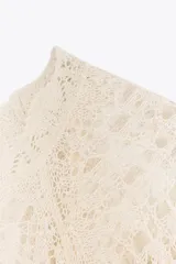 Vestido largo color crudo, tejido a crochet con diseño calado. Tiene cuello redondo, mangas cortas con volados y forro interior.
