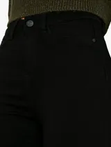 Pantalón de jean negro, tiro alto, corte skinny, cinco bolsillos y cierre frontal con botón.