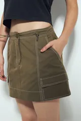 Falda corta tipo cargo de tiro medio, color negro, con costuras visibles en contraste blanco y bolsillos aplicados.