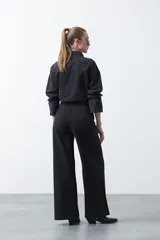 Jean wide leg de color negro con silueta amplia y caída fluida. Presenta detalles de tachas aplicadas que recorren el diseño en forma de ondas. Confeccionado en denim de algodón.