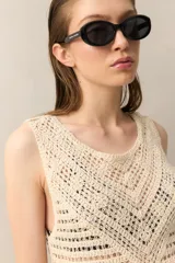 Vestido corto de crochet color crudo, sin mangas y con flecos en el ruedo.