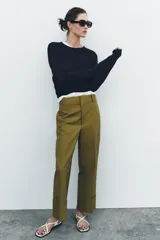 Pantalón color beige de corte ancho, con tiro medio, trabillas en la cintura y raya planchada.