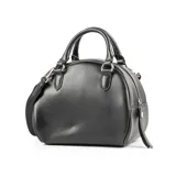 Cartera tipo baúl color negro con diseño tejido. Tiene doble asa corta, correa larga regulable y herrajes plateados.