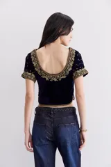 Top corto de terciopelo azul marino con escote redondo y mangas cortas. Presenta apliques bordados en hilo de lurex dorado, piedras y mostacillas.