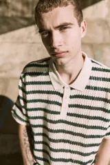 Polo de punto color crema con rayas horizontales verde oscuro, cuello clásico y cierre de botones.