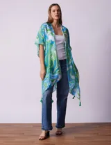 Kimono tejido con estampado abstracto en tonos verde, azul y blanco. Tiene mangas cortas amplias y terminación con borlas verdes en el ruedo.