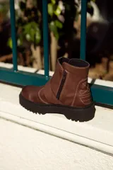 Bota corta color marrón de cuero, con hebilla metálica y cierre lateral.