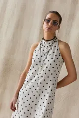 Vestido midi de lino color crudo con lunares negros, escote halter y espalda con cierre invisible y botón al cuello.
