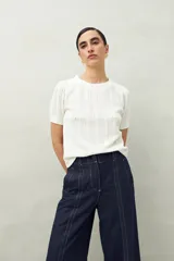Top blanco tejido con trama en relieve, mangas cortas abullonadas y cuello redondo.