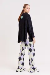 Pantalón de punto con estampado geométrico en tonos lila, verde y beige.